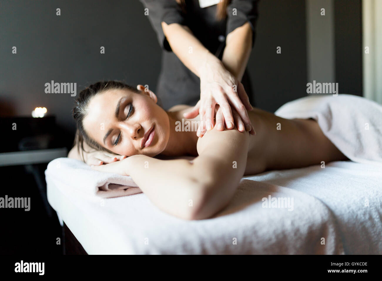 Schöne, junge und gesunde Frau, die ihre Schulter und Körper massiert durch einen professionellen Masseur in einem Spa-Zentrum Stockfoto