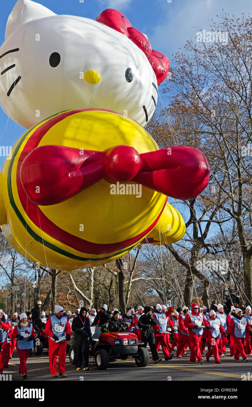 Ein Team von Handlern begleitet den Hello Kitty Ballon, Central Park West in die Macy's Thanksgiving Day Parade in New York City. Stockfoto