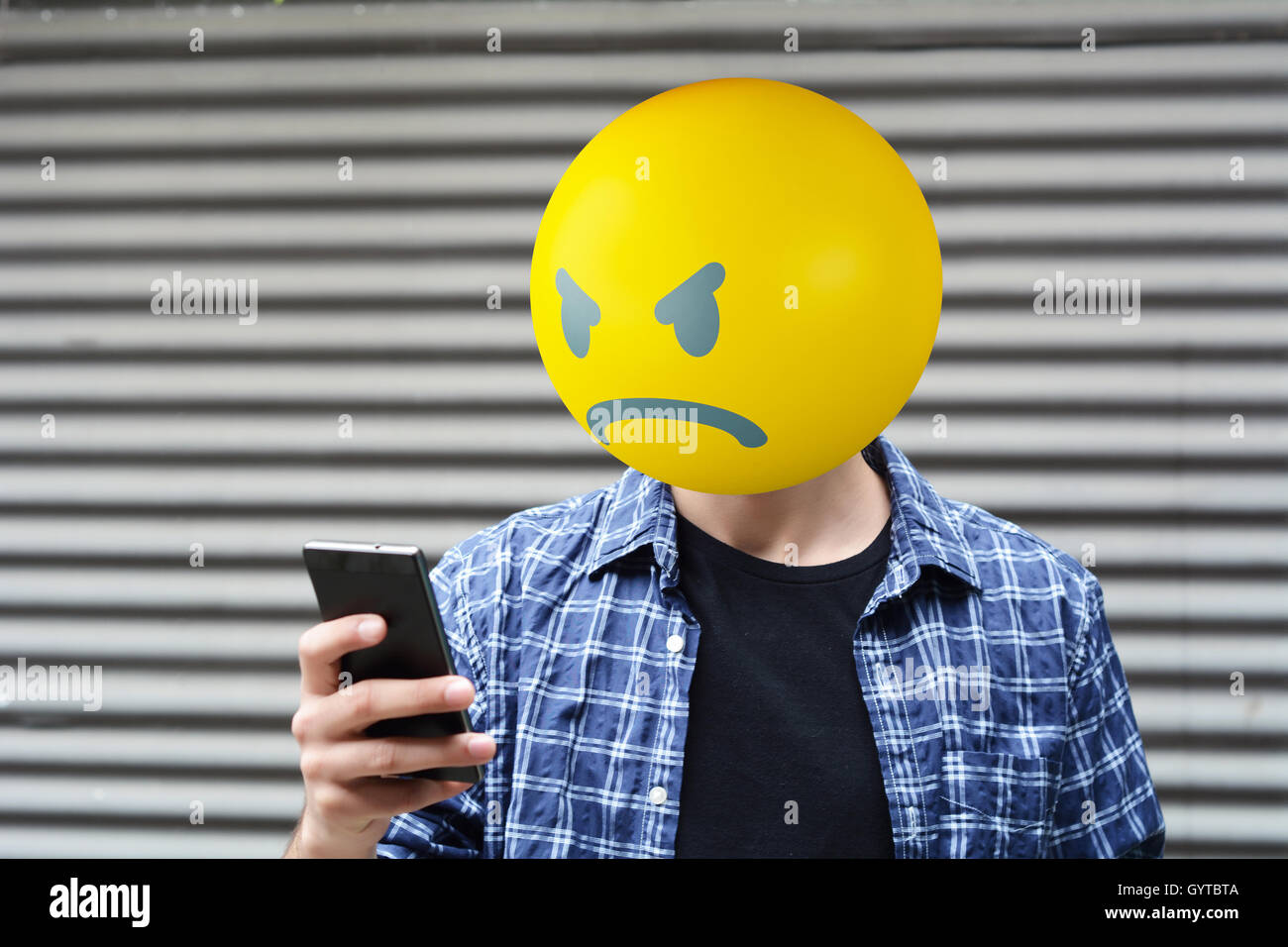 Wütend Emoji Kopf Mann mit einem Smartphone. Stockfoto