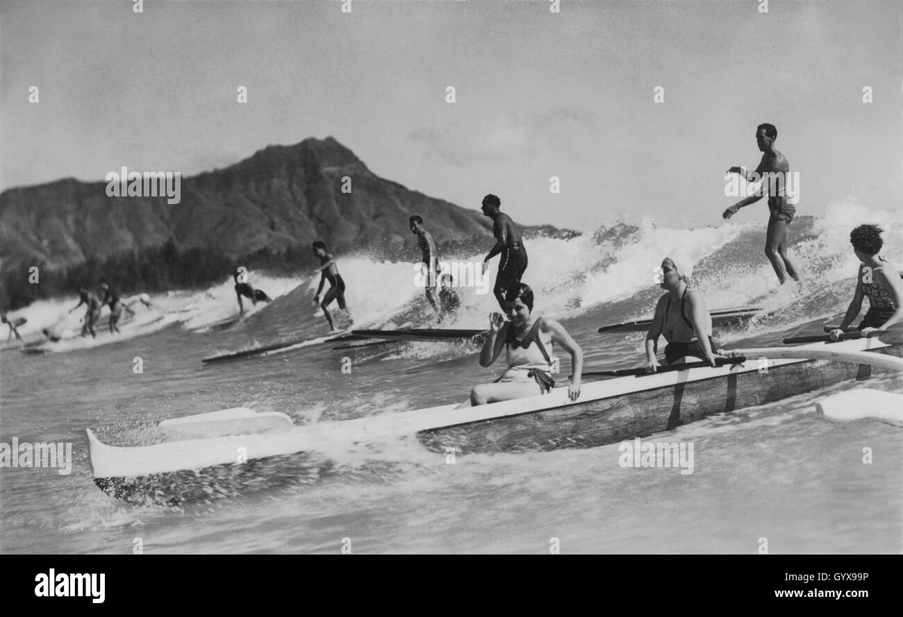 Vintage Waikiki, Honolulu Blick auf das Surfen, mit Männern auf Holzsurfbrettern und Frauen in einem Outrigger Boot. Foto von Tom Blake, 1931. Stockfoto