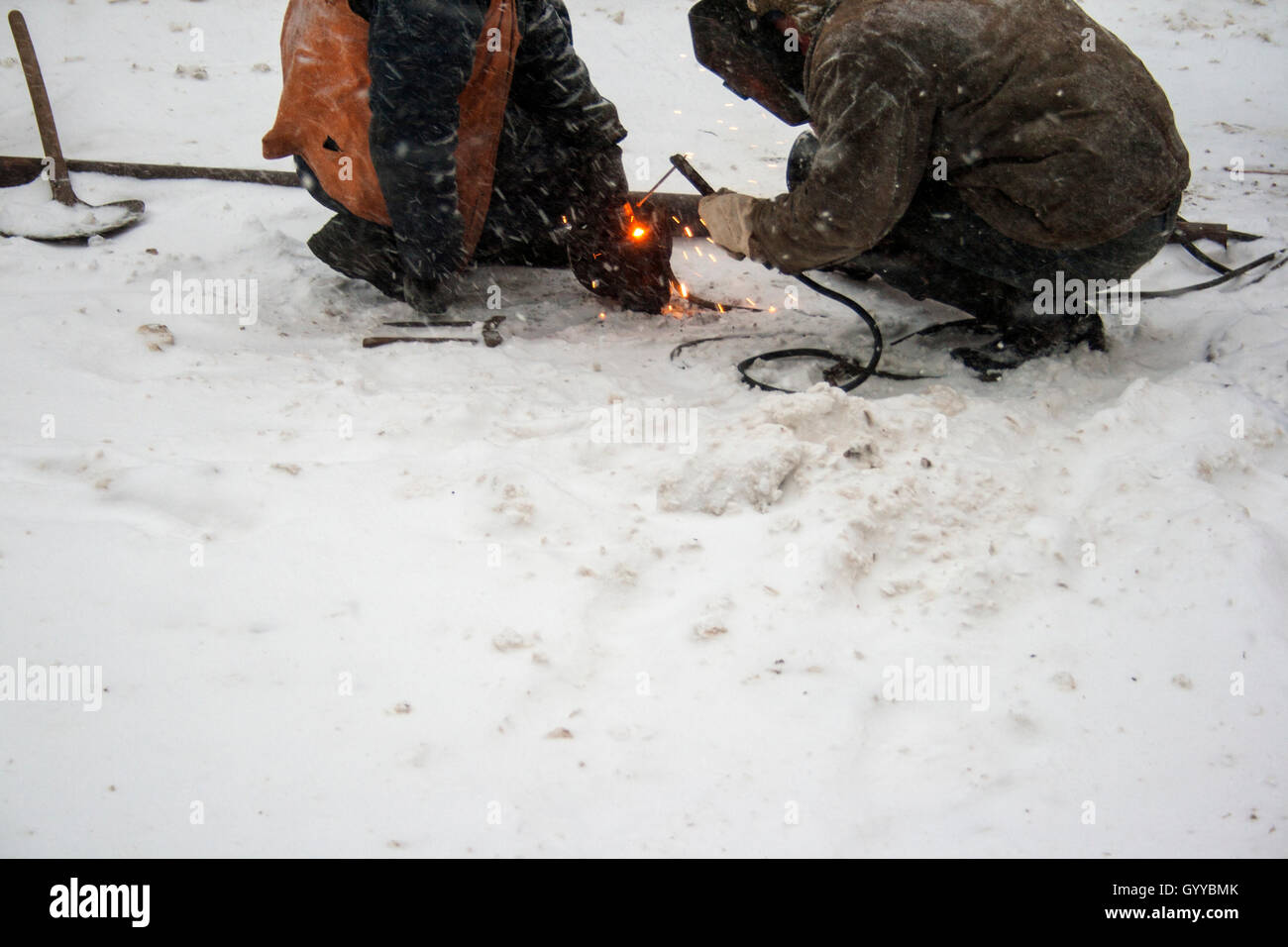 Schweißer arbeiten auf Schnee während eines Schneefalls Stockfoto