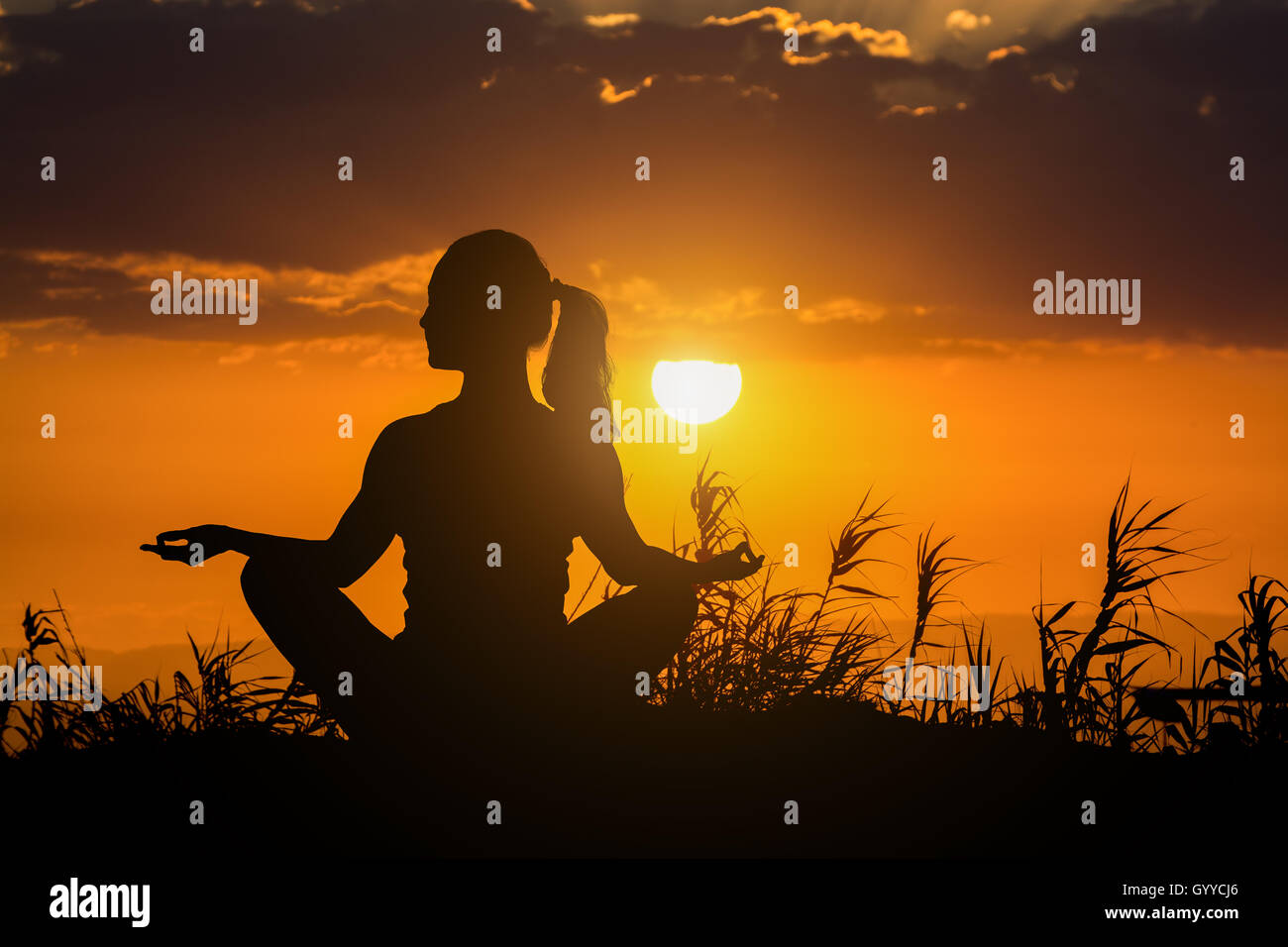 Gesunde Frau beim Yoga im Freien, Sonnenuntergang über Meer, Körper Meditation Pflegekonzept Stockfoto