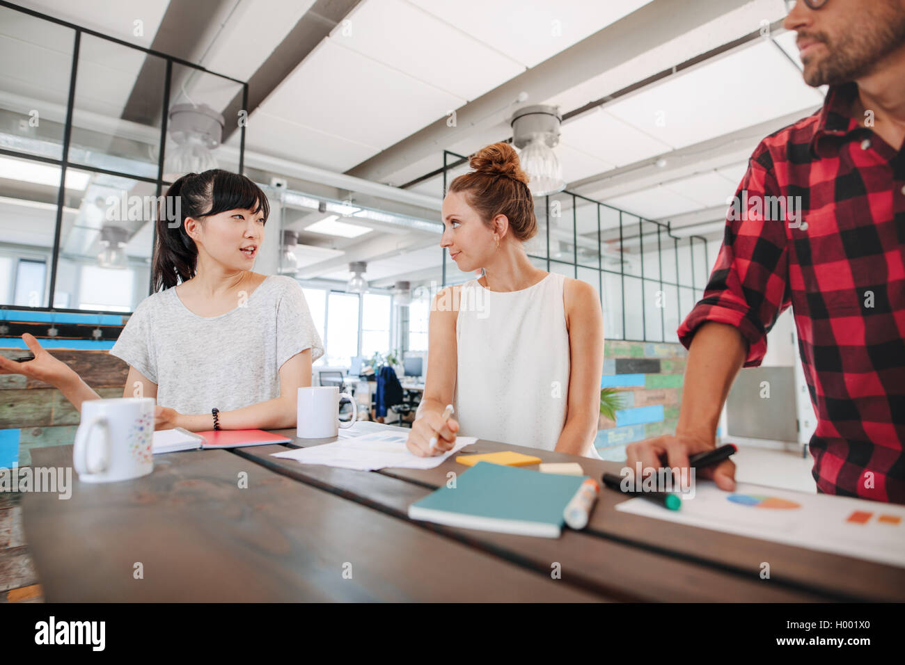 Gruppe von Jugendlichen, die während einer Besprechung Tisch in Startup Büro brainstorming. Vielfältiges Team von Geschäftspartnern zu diskutieren Stockfoto