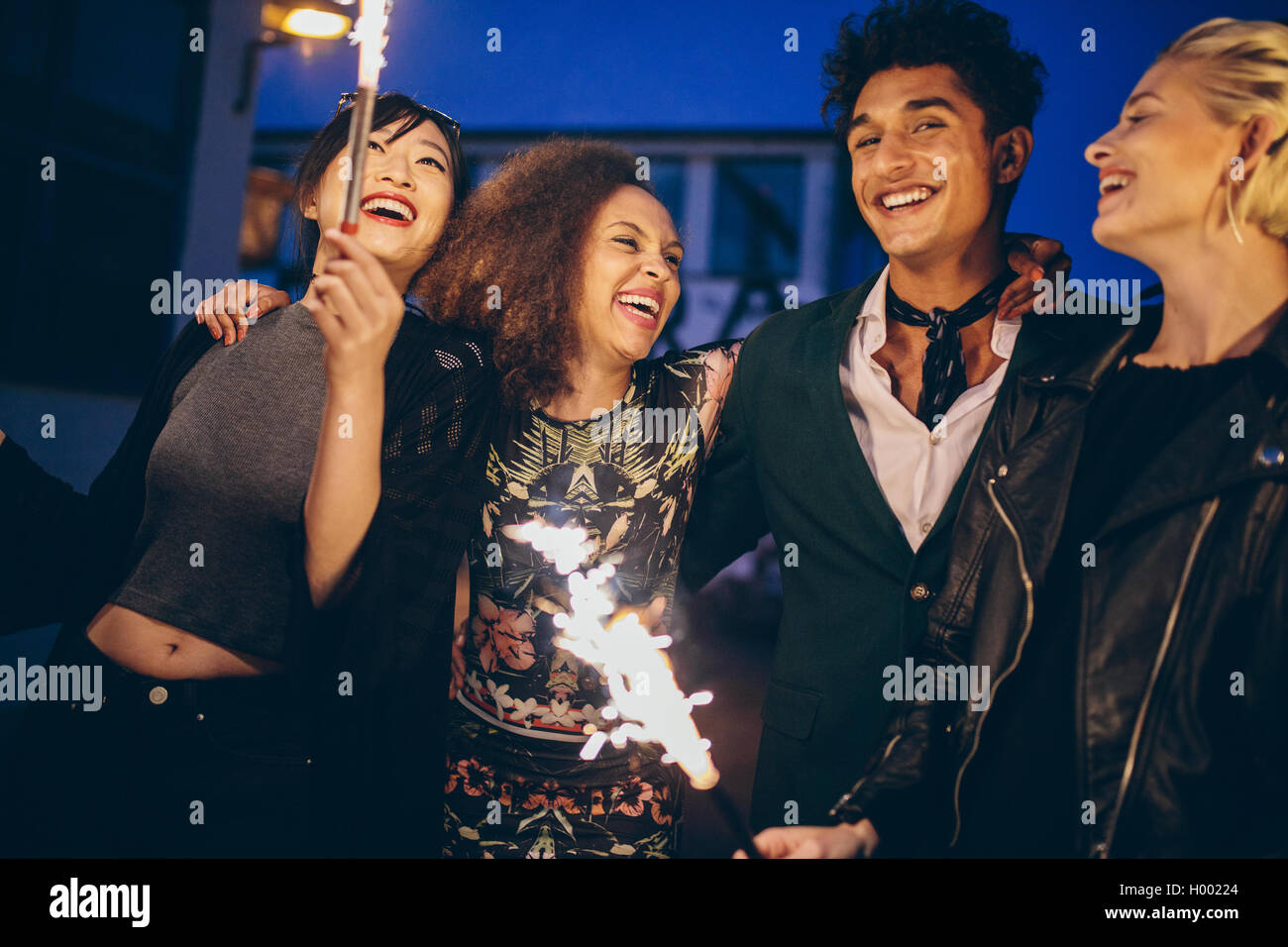 Aufnahme des jungen Menschen und Frauen in der Stadt bei Nacht mit Feuerwerk. Gruppe von Freunden mit Wunderkerzen auf Straße Abend genießen. Stockfoto
