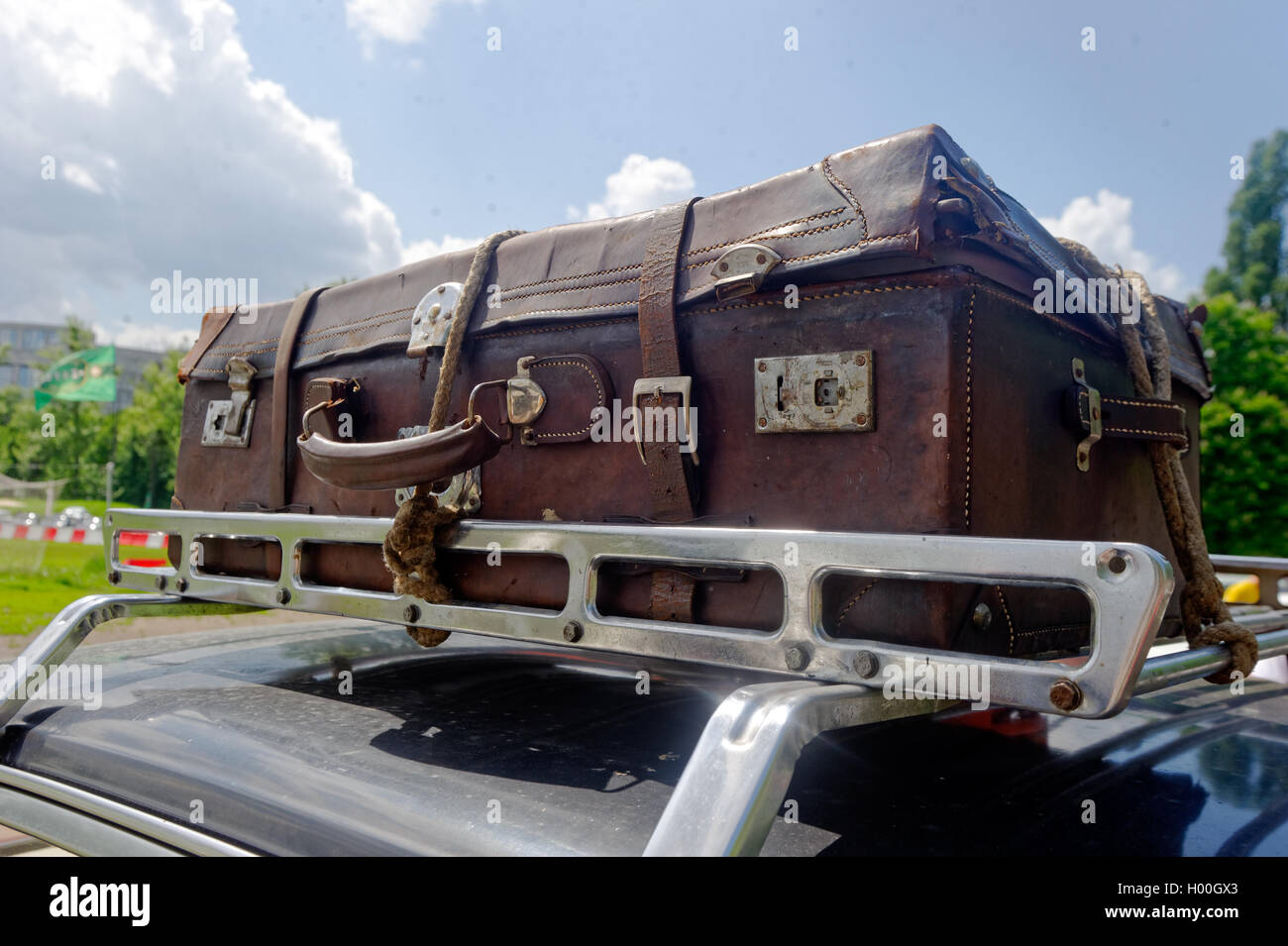 Braune Vintage Reisetasche auf dem Auto Dachgepäckträger an einem sonnigen Sommertag gegen den blauen Himmel Stockfoto