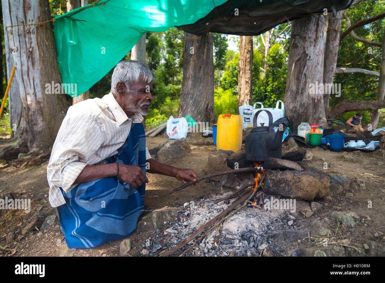 ELLA, SRI LANKA - 2. März 2014: älterer Mann kochendes Wasser in einem Topf auf Lagerfeuer im Wald. Stockfoto