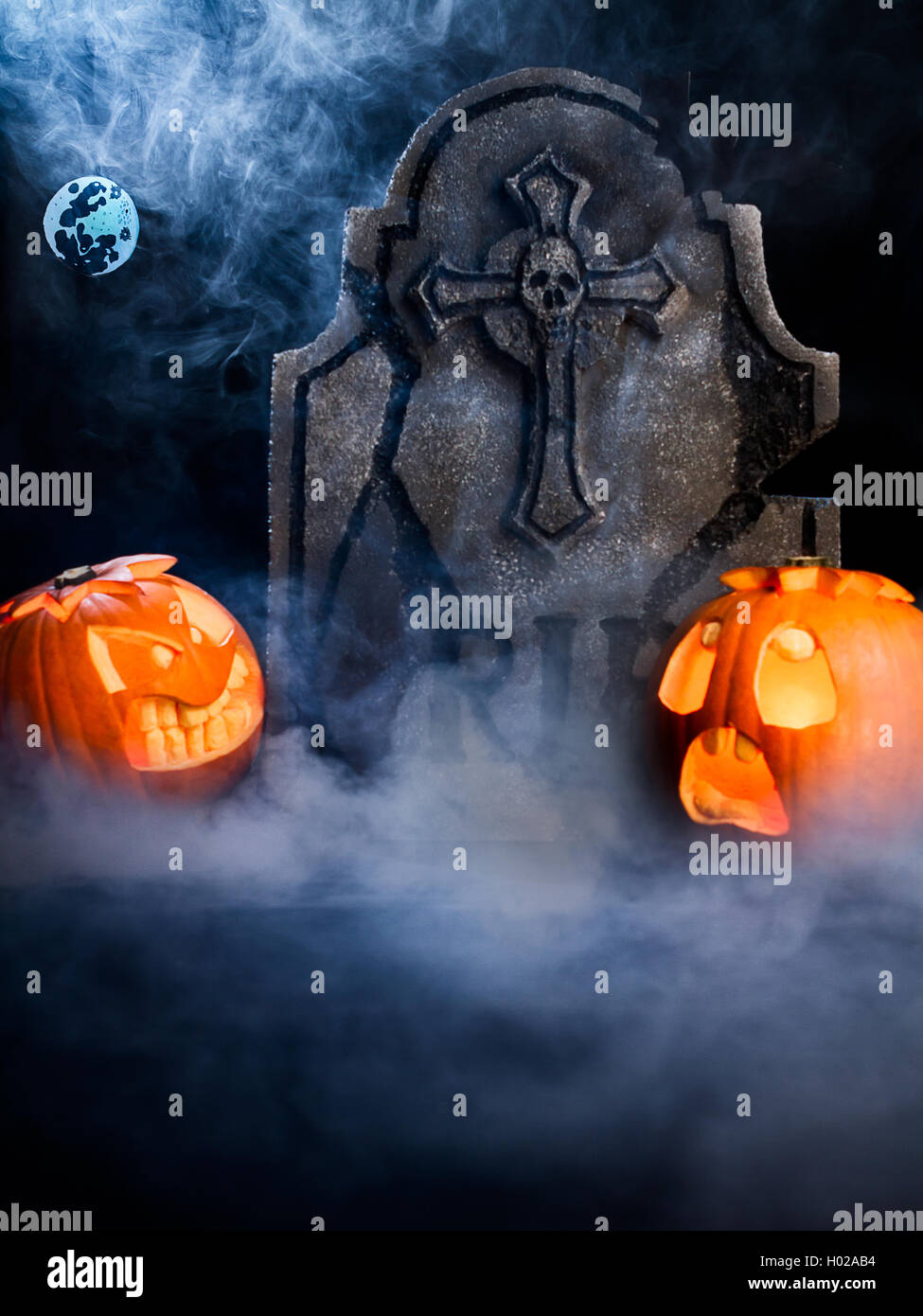 Wütend das Gesicht und erschrocken angesichts des Halloween Kürbisse mit Mond, Grabstein und bat auf Misty dunklen Hintergrund. Stockfoto