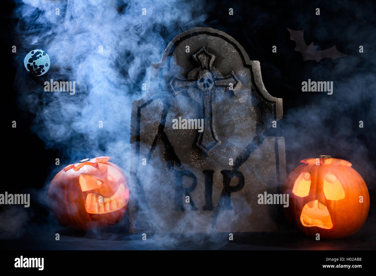 Wütend das Gesicht und erschrocken angesichts des Halloween Kürbisse mit Mond und Tombstone auf Misty dunklen Hintergrund. Stockfoto