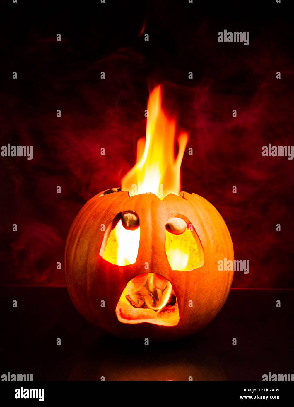 Angst angesichts der Halloween Kürbis mit Flammen und roten Rauch im Hintergrund. Stockfoto