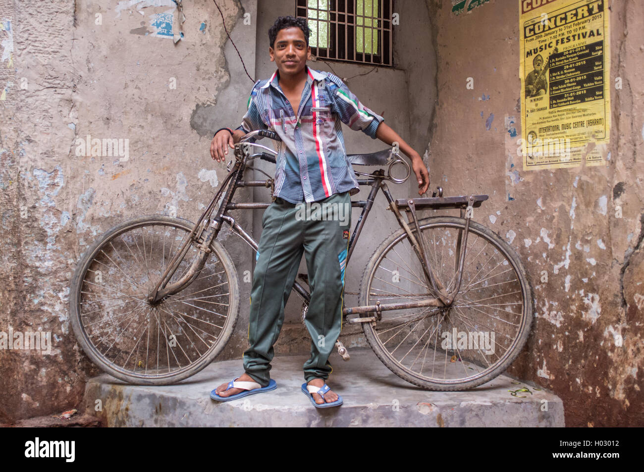 VARANASI, Indien - 25. Februar 2015: Indianerjunge steht neben traditionellen Fahrrad Teil in der Ecke der Straße. Stockfoto