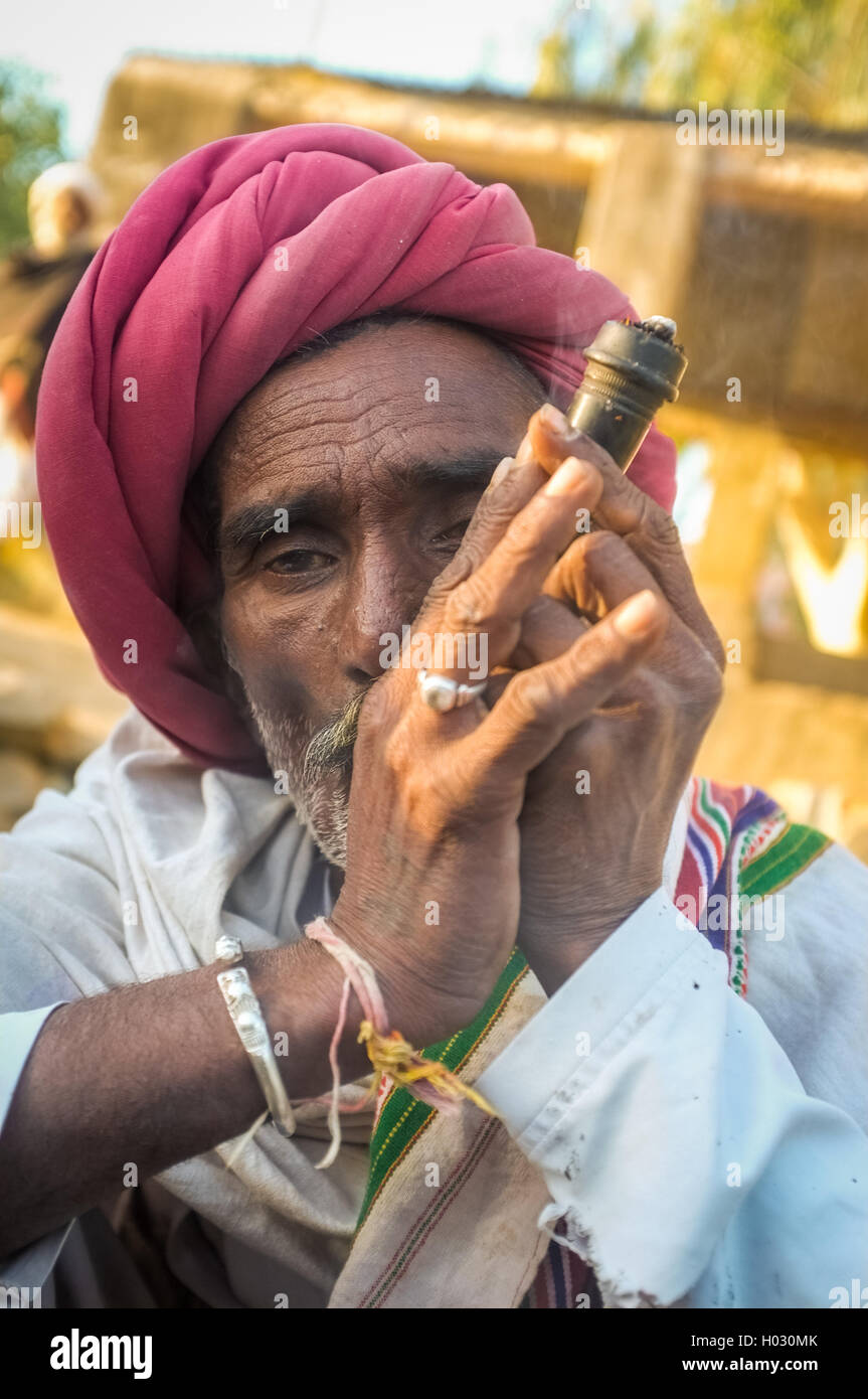 GODWAR REGION, Indien - 14. Februar 2015: ältere Rabari Stammesangehörige mit roten Turban und Decke raucht Chillum. Rabari oder Rewari ein Stockfoto