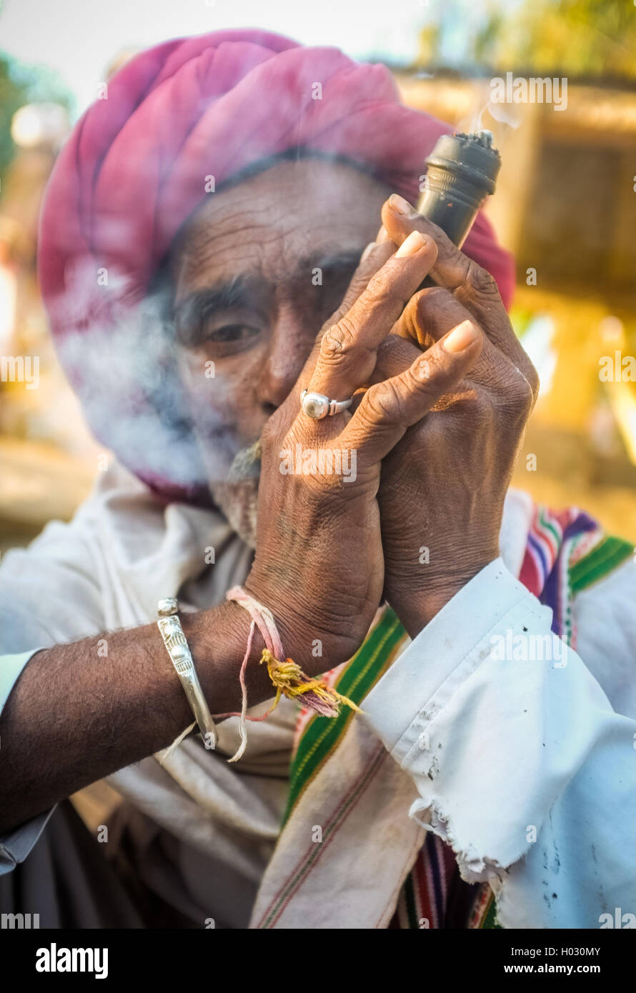 GODWAR REGION, Indien - 14. Februar 2015: ältere Rabari Stammesangehörige mit roten Turban und Decke raucht Chillum. Rabari oder Rewari ein Stockfoto
