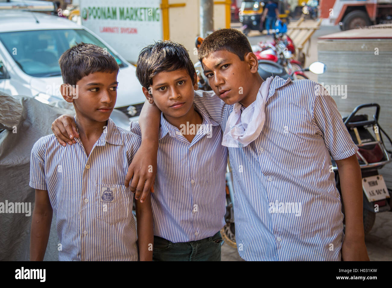 MUMBAI, Indien - 16. Januar 2015: drei junge Burschen in Schuluniformen stehen in der Straße zusammen mit Händen auf der jeweils anderen Seite Stockfoto