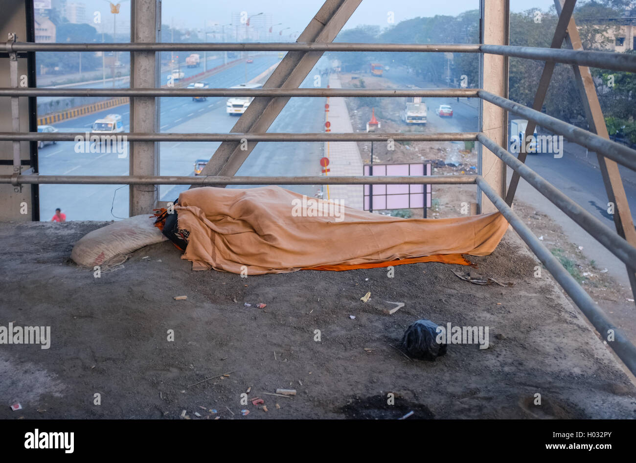 MUMBAI, Indien - 5. Februar 2015: Person schläft auf Überführung auf schmutzigen Boden mit ganzen Körper unter Decke bedeckt. Gemeinsamen Szene Stockfoto