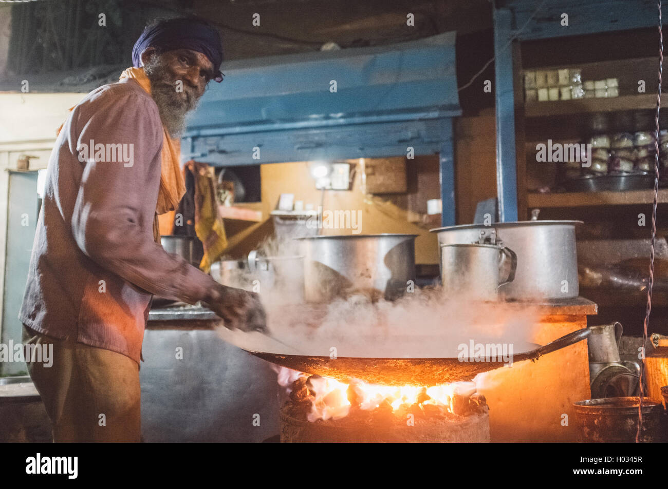 VARANASI, Indien - 21. Februar 2015: Straße Verkäufer kocht Essen in großen Pfanne auf Kohle Ofen in der Nacht. Nachbearbeitet mit Korn, textur Stockfoto