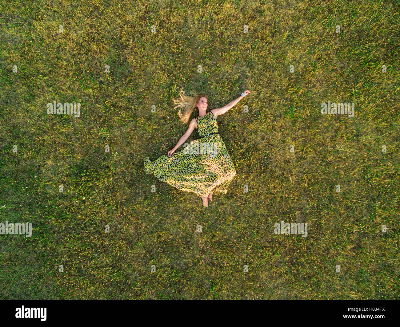 Luftaufnahme der junge Frau in einem grünen Kleid legen Sie sich auf eine Wiese. Stockfoto