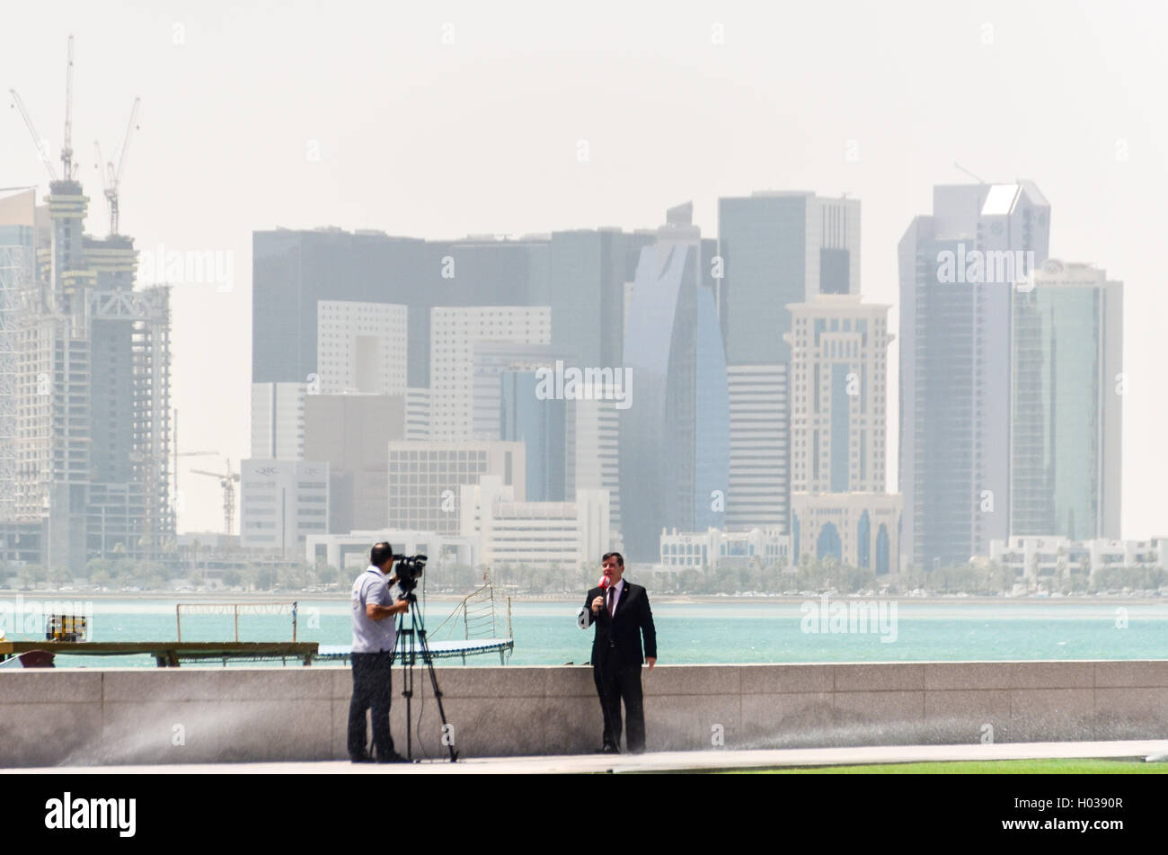 Interview mit Kameramann und Lautsprecher in Doha mit der West Bay Finanzviertel im Hintergrund Stockfoto