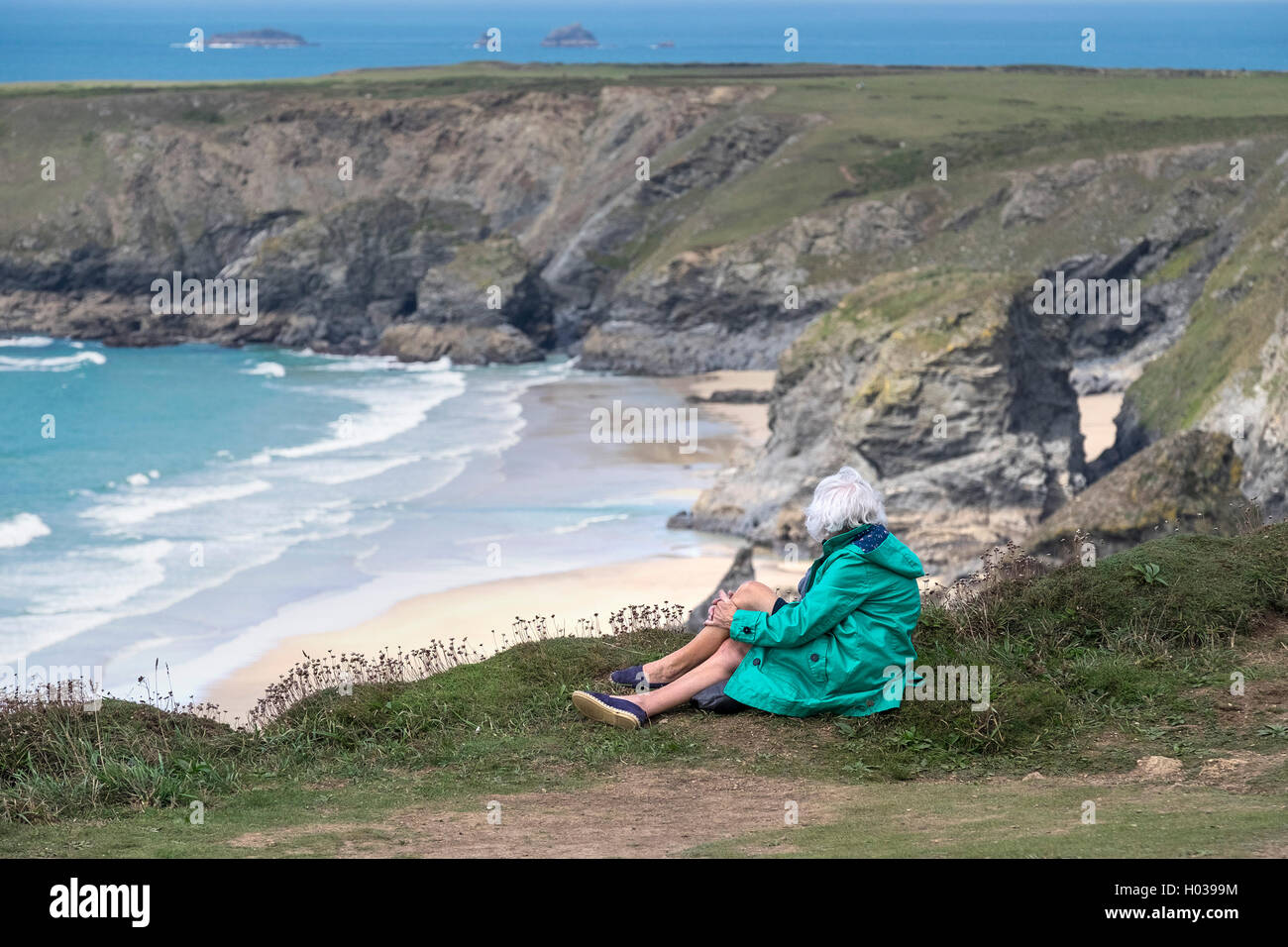 Ein Tourist ruht und genießt die Aussicht auf Carnewas bei Bedruthan in Cornwall. Stockfoto