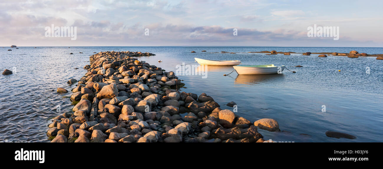 Zwei weiße Rudern Boote hinter Cobble Stone Mole im Meer bei Sonnenuntergang Stockfoto