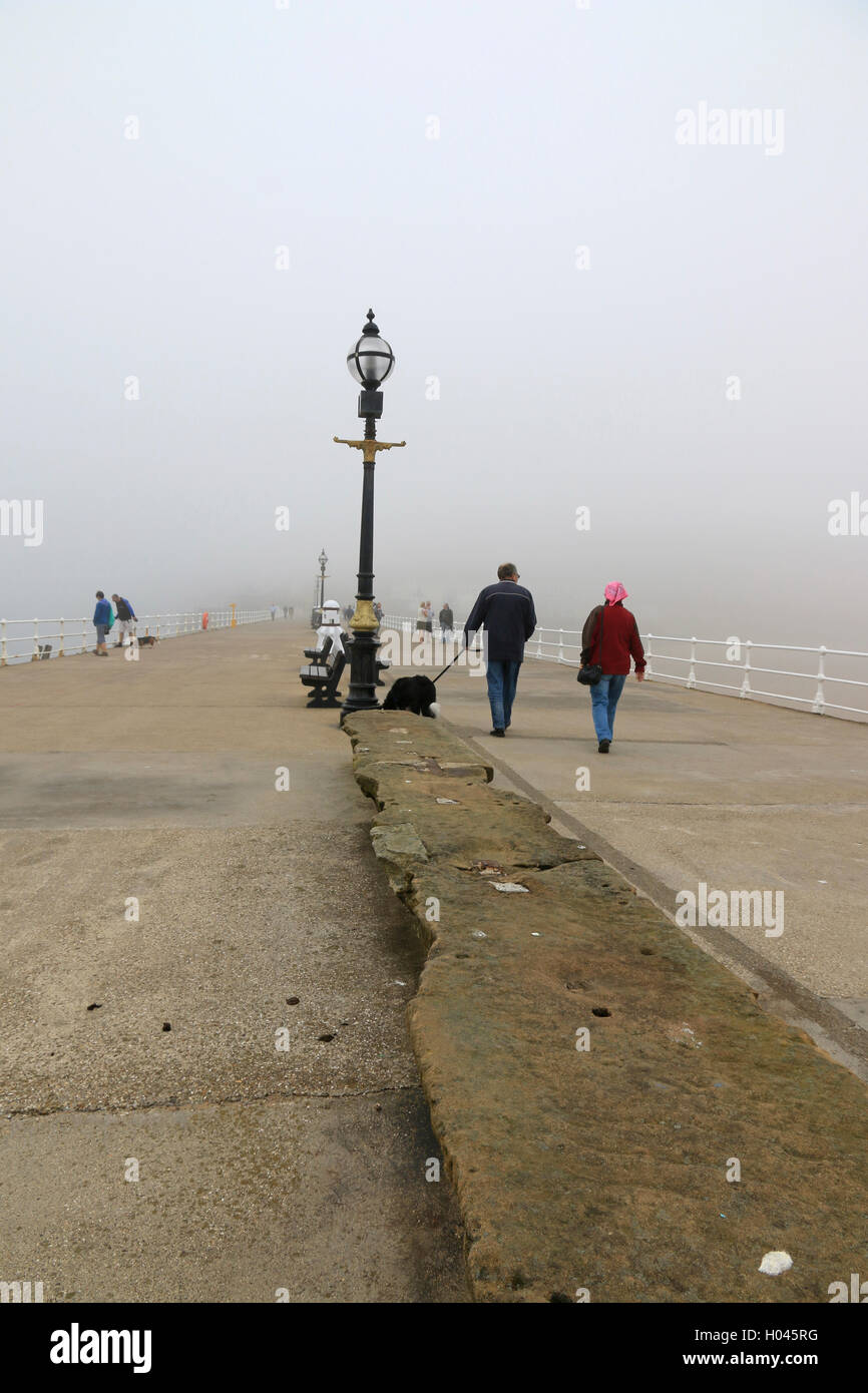 Paar Whitby West Pier an einem nebeligen Tag entlang Stockfoto