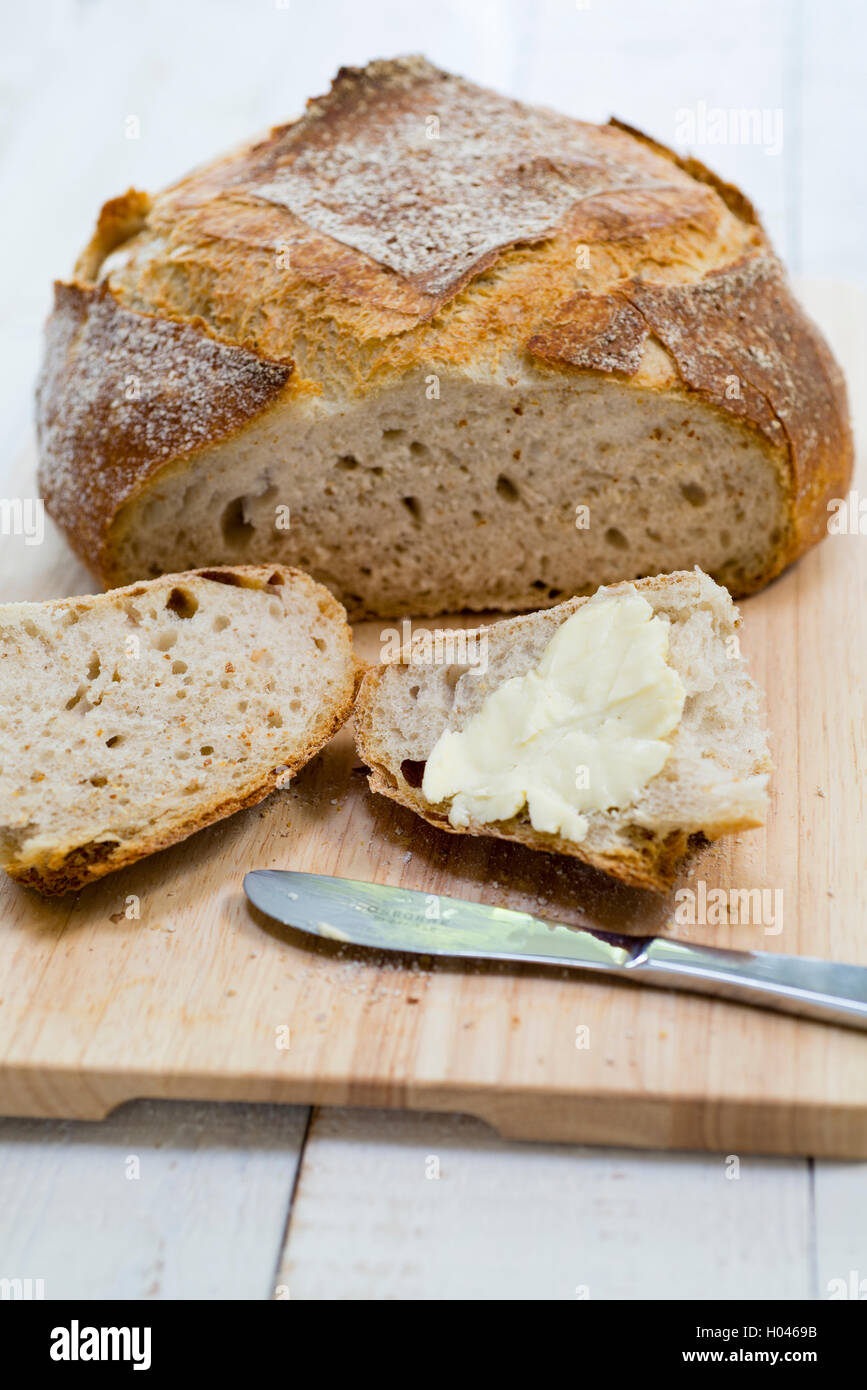 Eine Scheibe Brot und Butter aus einem frisch gebackene hausgemachte Sauerteig Brot geschnitten. Stockfoto