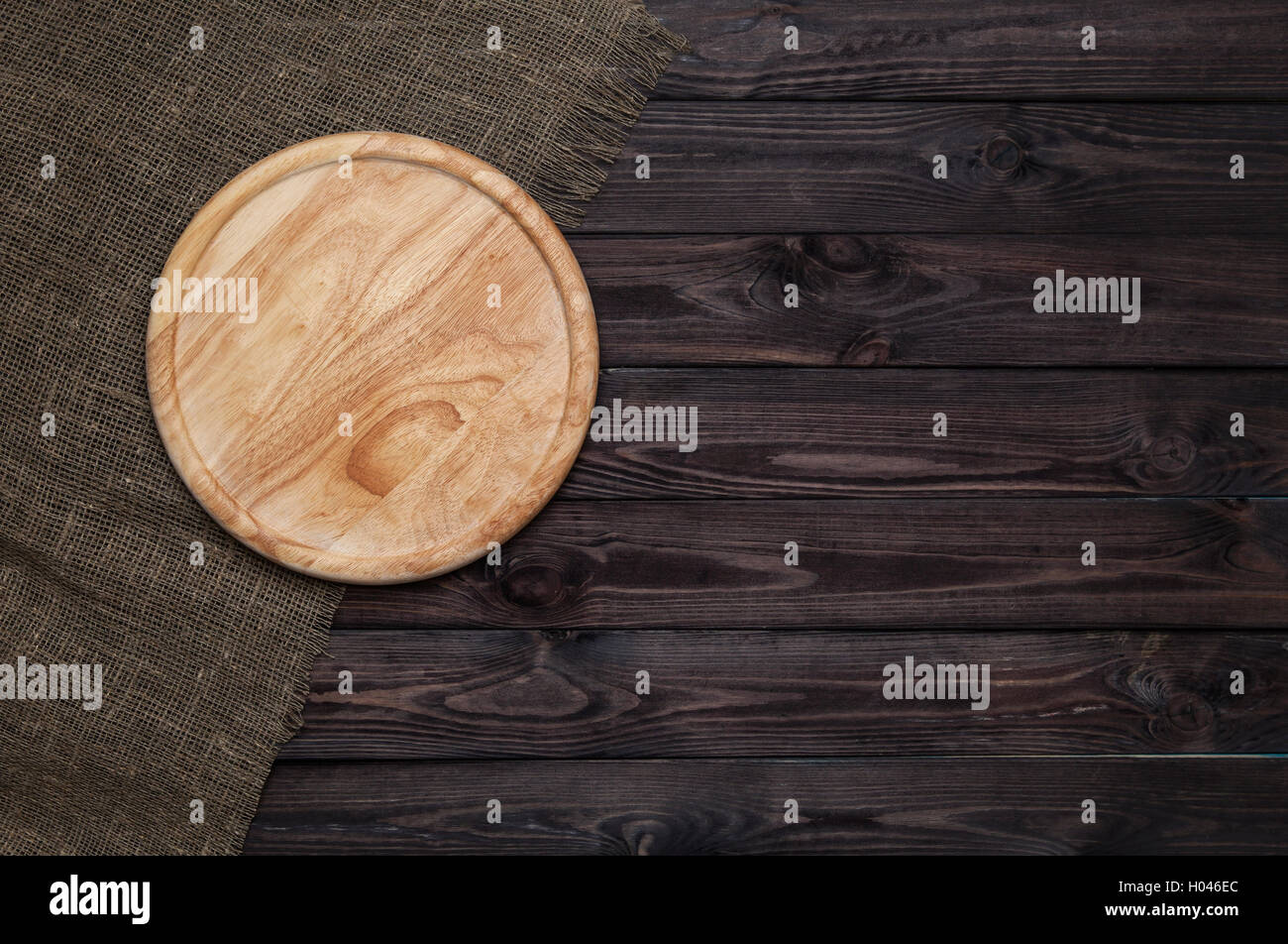 Rundes Schneidebrett auf dunklen Holztisch Stockfoto