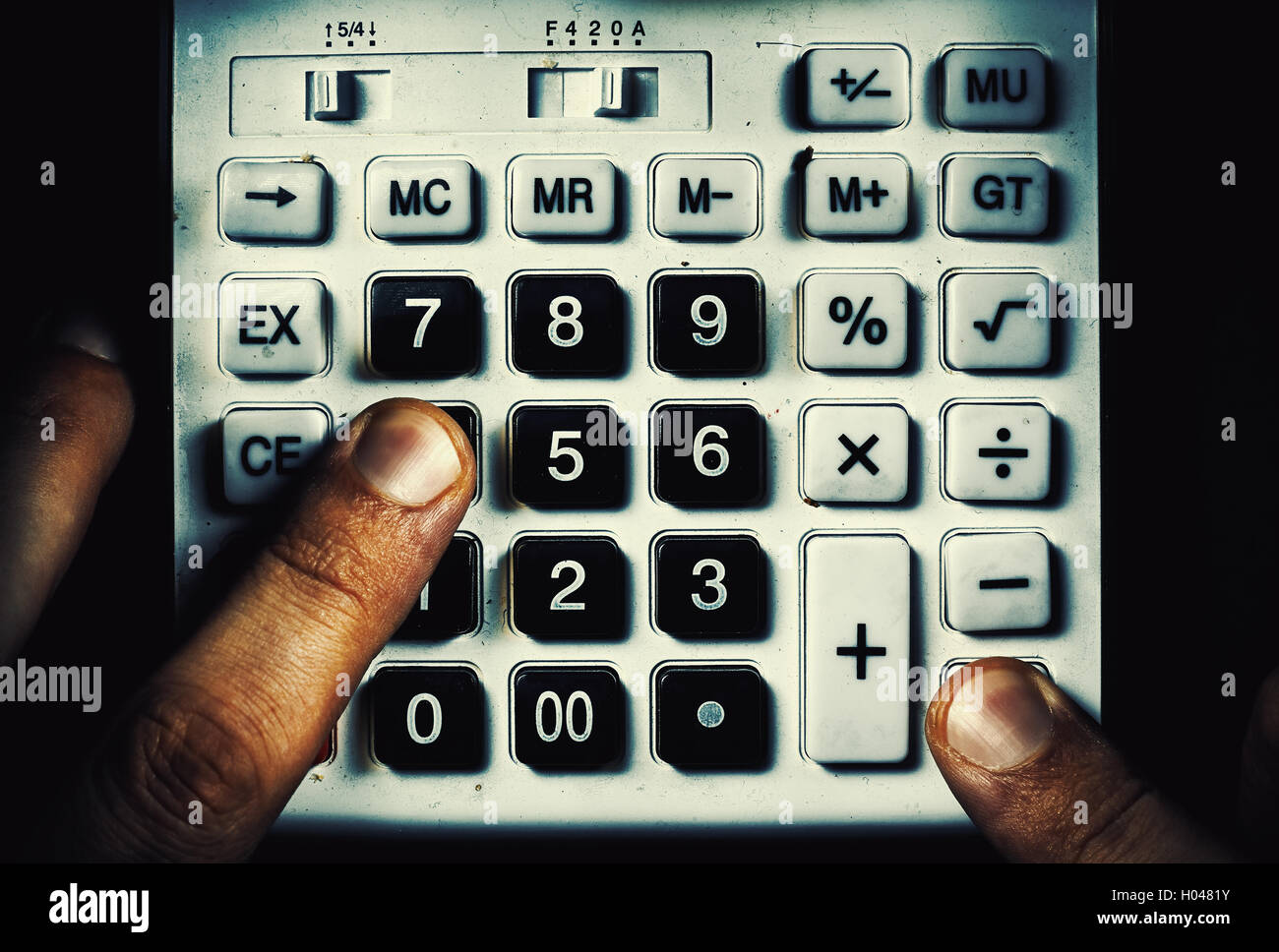 Konzeptuelle Komposition über Berechnung, zwei Finger auf ein alten staubigen Taschenrechner-Tasten. Stockfoto