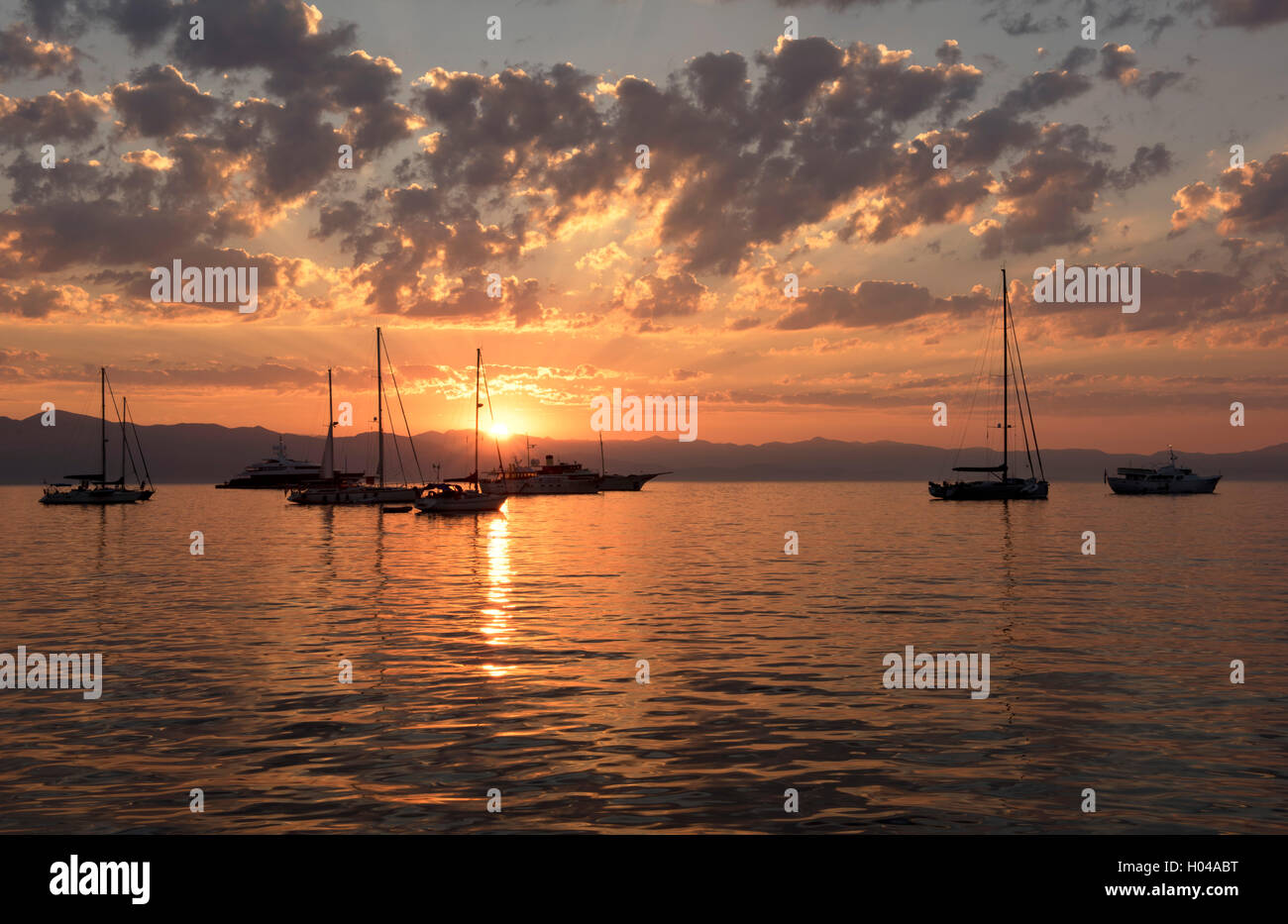 Sonnenaufgang hinter Segelbooten und Yachten vor Anker im Hafen von Gaios, Paxos, die Ionischen Inseln, die griechischen Inseln, Griechenland, Europa Stockfoto