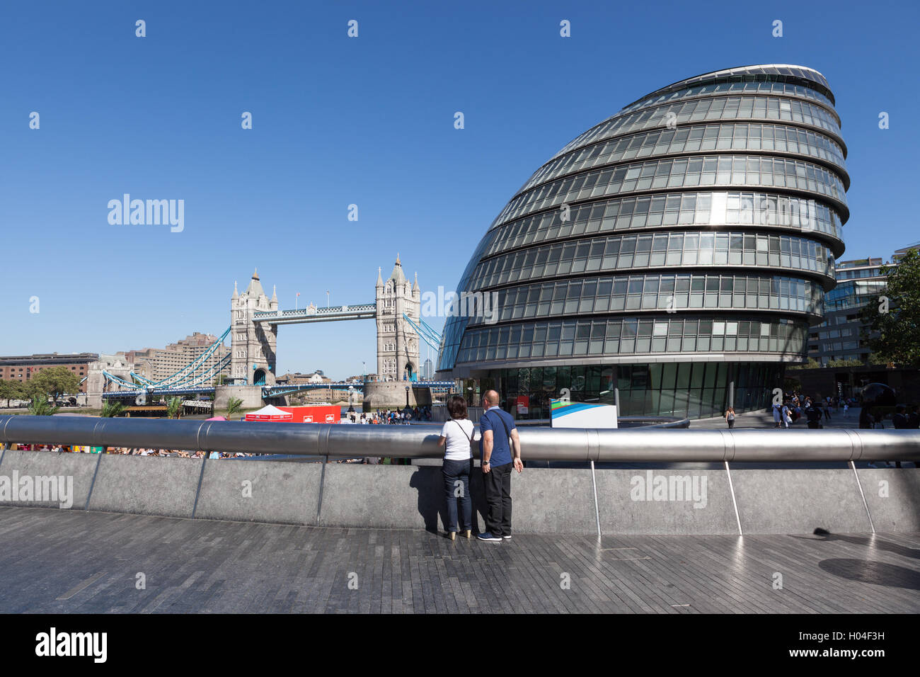 Touristen, die gerne an der Tower Bridge in der Nähe von der Glaskuppel des Rathauses. Stockfoto Touristen, die gerne an der Tower Bridge in der Nähe von der Glaskuppel des Rathauses. Stockfoto