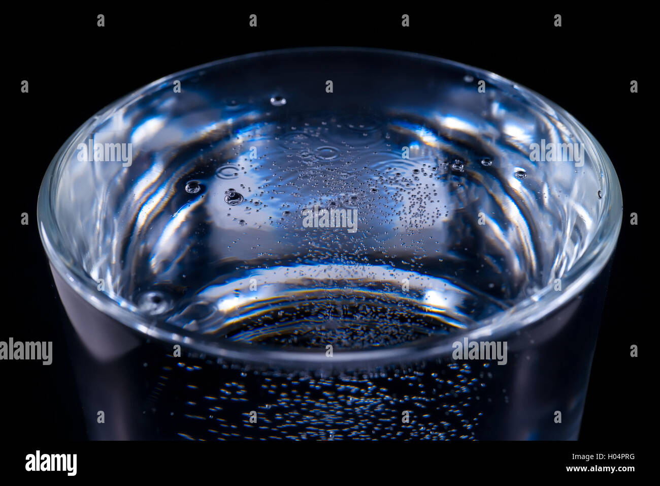 Wasseroberfläche mit Luftblasen im Glas. Auf schwarzem Hintergrund Stockfoto