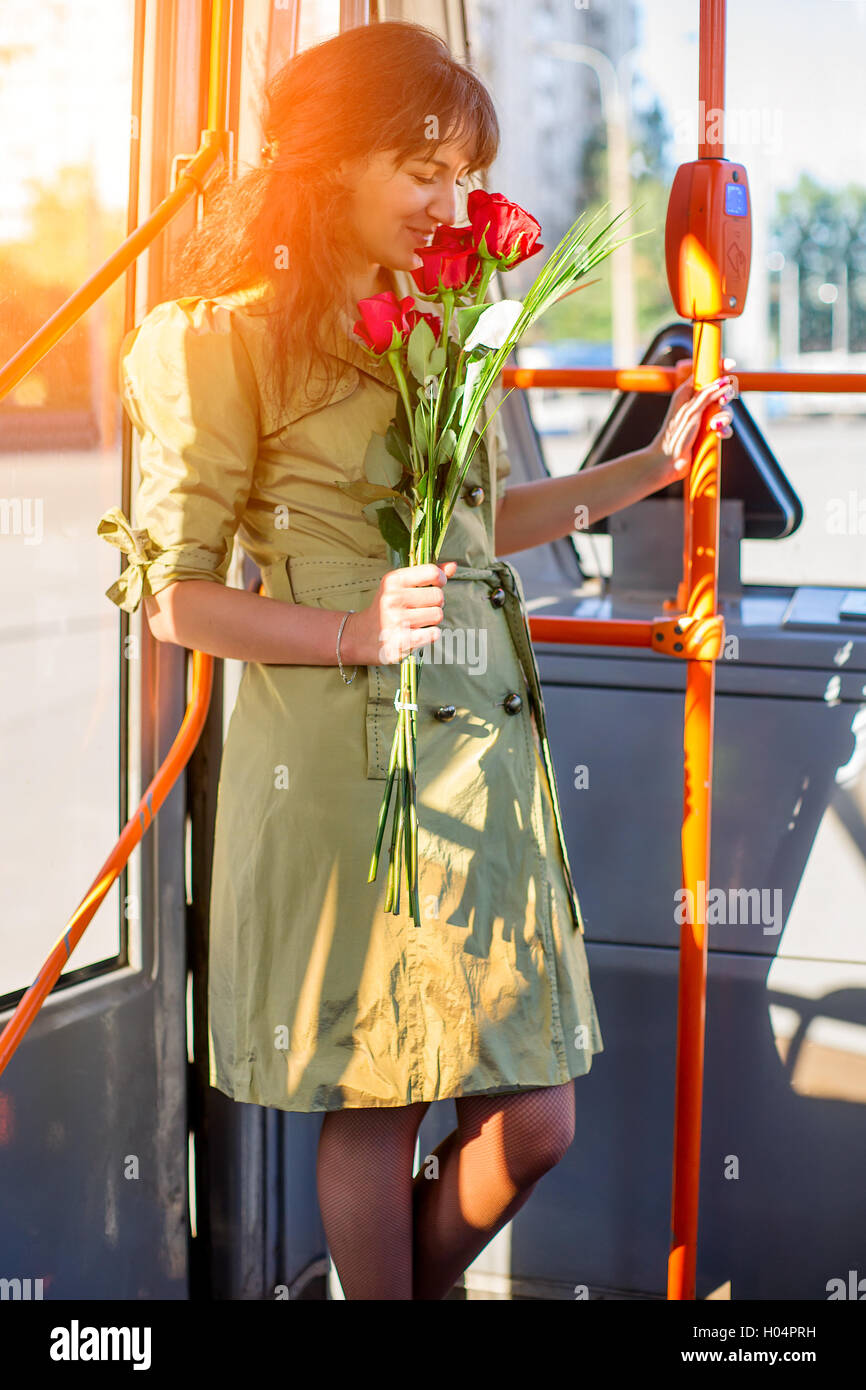 Glückliche Frau in lässig mit rose Bouquet in Straßenbahn bleiben. Romantik, dating und Feier-Konzept Stockfoto