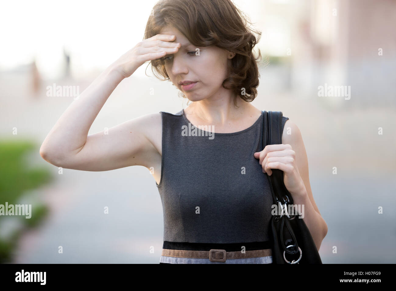 Porträt des jungen Büro Frau auf der Straße laufen, im Sommer, runzelt die Stirn, hielt ihren Kopf mit der Hand, hat Geschäftsfrau forgotte Stockfoto