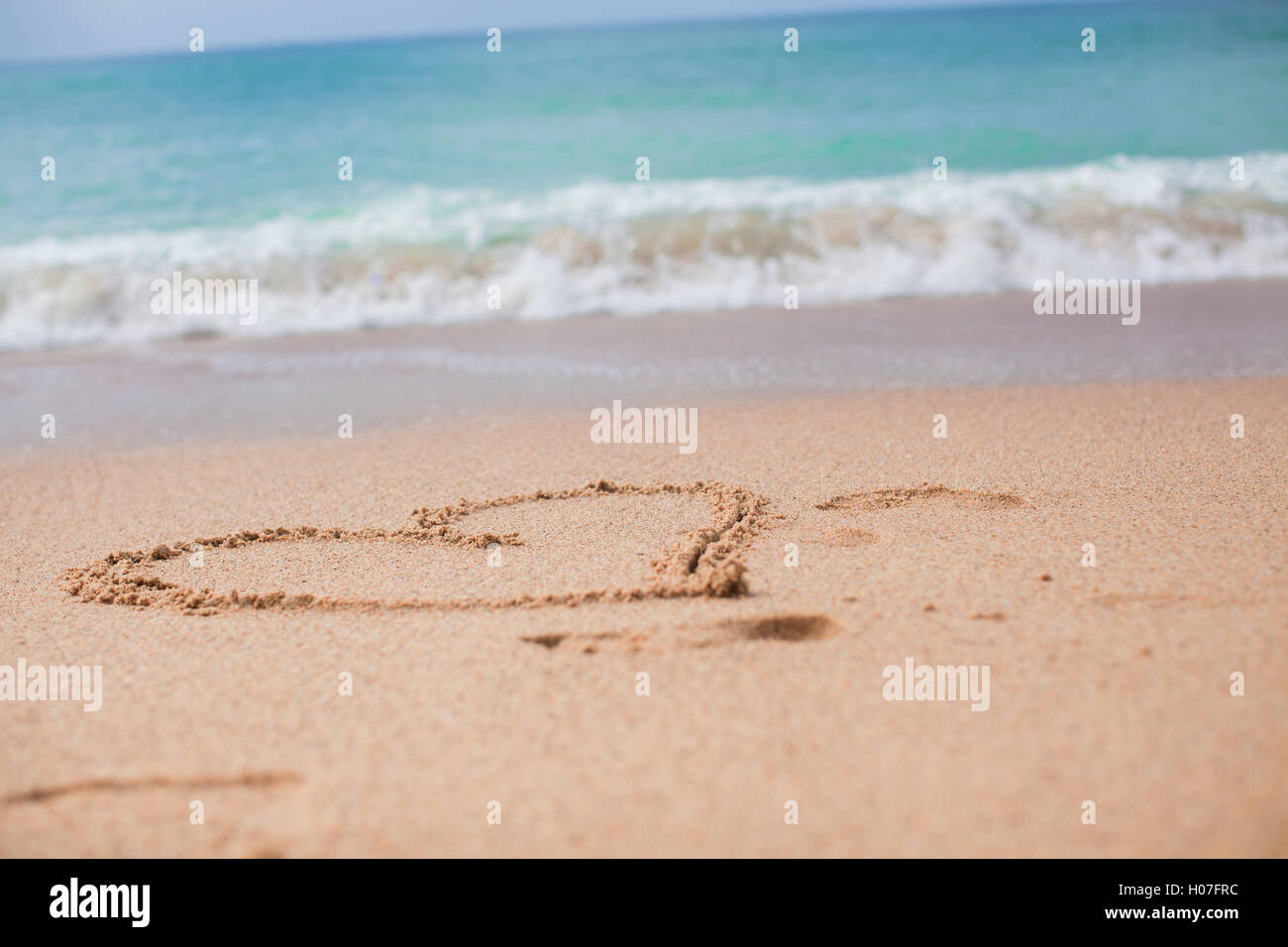 Herzen in den Sand an einem tropischen Strand gemalt Stockfoto