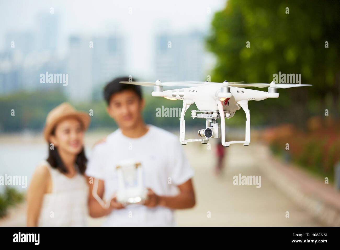 junge asiatische paar eine Drohne in einem Stadtpark, selektiven Fokus auf die Drohne in Betrieb Stockfoto