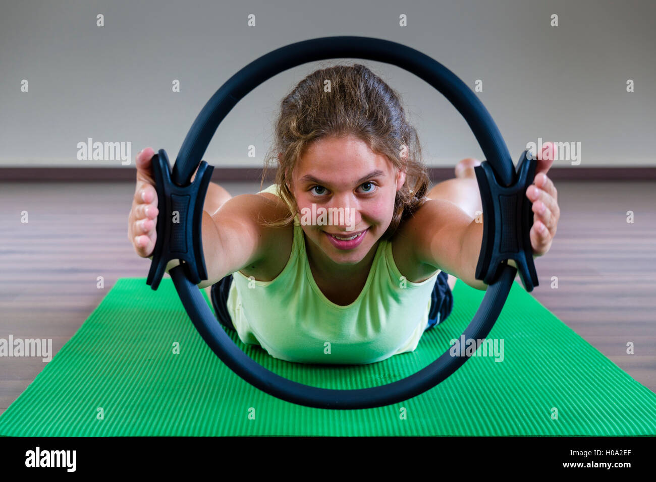 Eine junge Frau Training Pilates ist, Halten und schauen durch den Ring, Deutschland Stockfoto