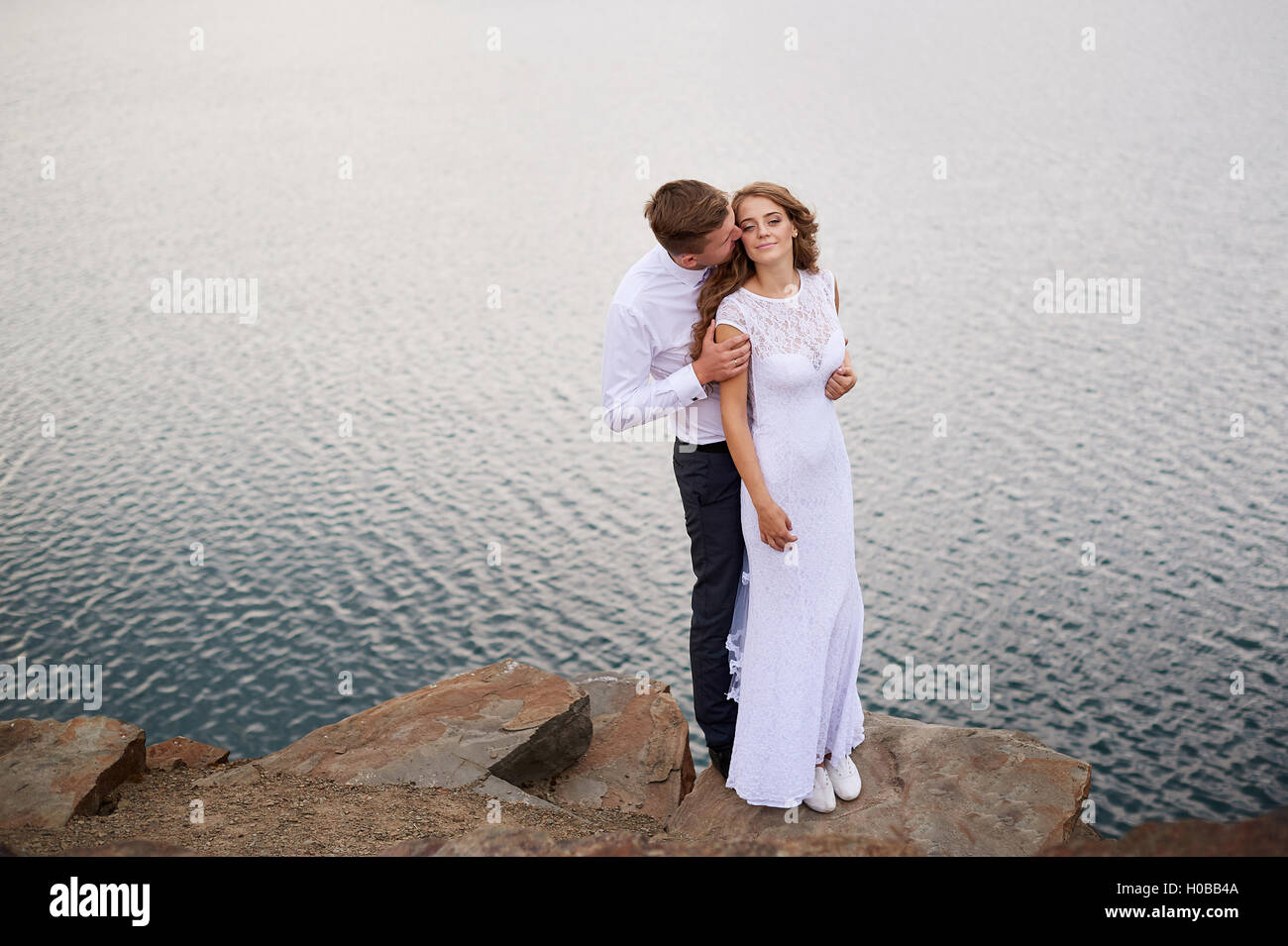 liebende Braut und Bräutigam zu Fuß auf einem Hintergrund von See Stockfoto
