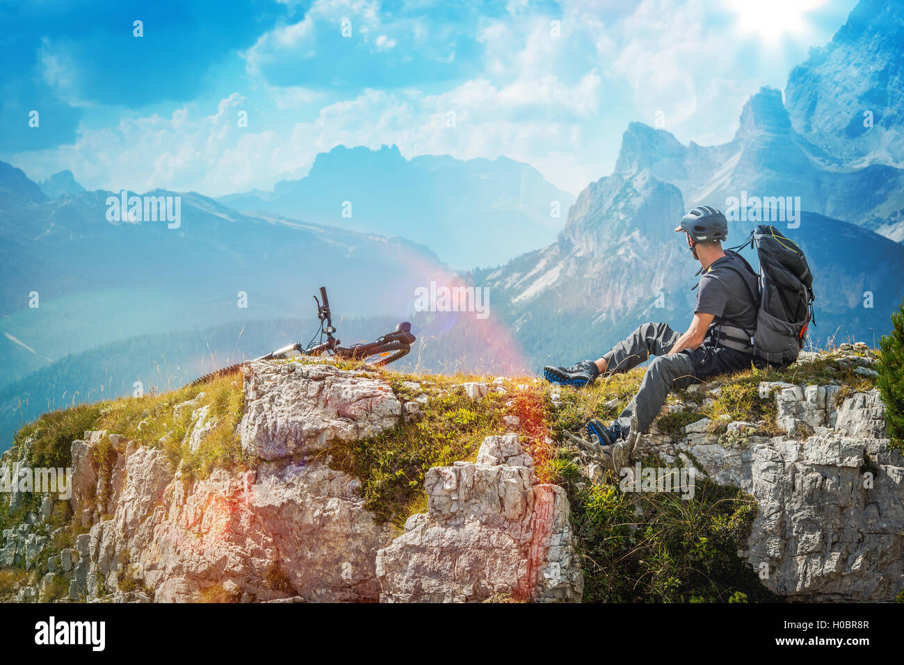 Radfahrer auf dem Radweg ruht auf den Felsen und malerischen Blick auf die Berge genießen. Bike-Thema. Stockfoto