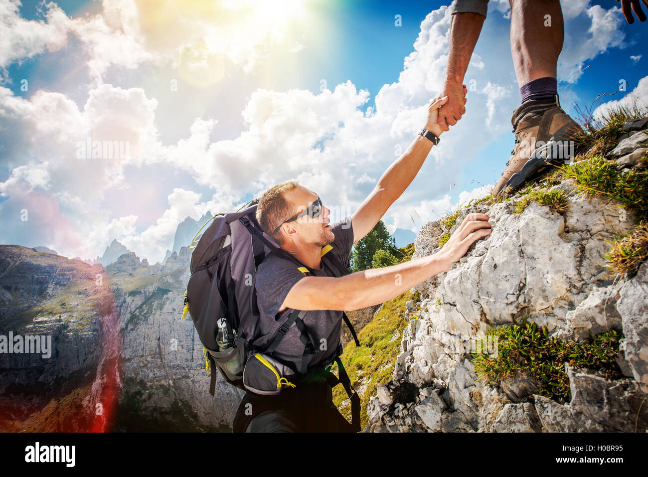 Freundliche Hand auf die Hochgebirge Wanderung. Männer, die anderen Wanderer zu helfen, indem man ihm die Hand. Thema Wandern. Stockfoto