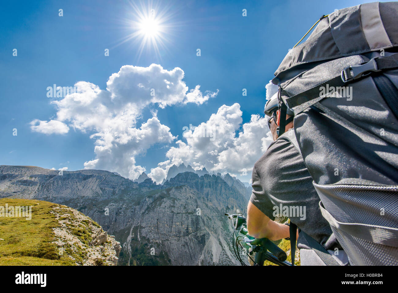 Mountain Bike Tour. Kaukasische Sportler mit Rucksack auf seinem Fahrrad in der Hochgebirgs-Landschaft während sonnigen Sommertag. Stockfoto