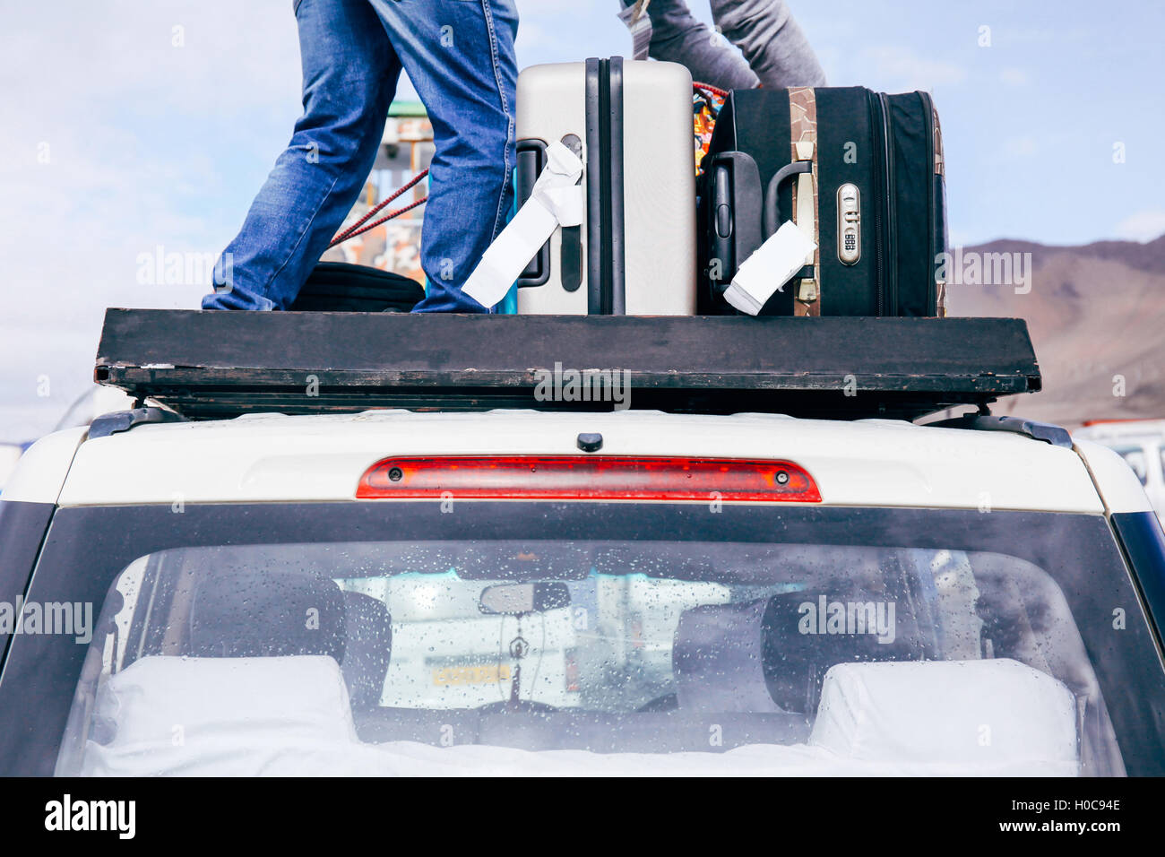 Koffer und Taschen auf dem Autodach bereit für eine Reise im Himmelshintergrund angeordnet Stockfoto