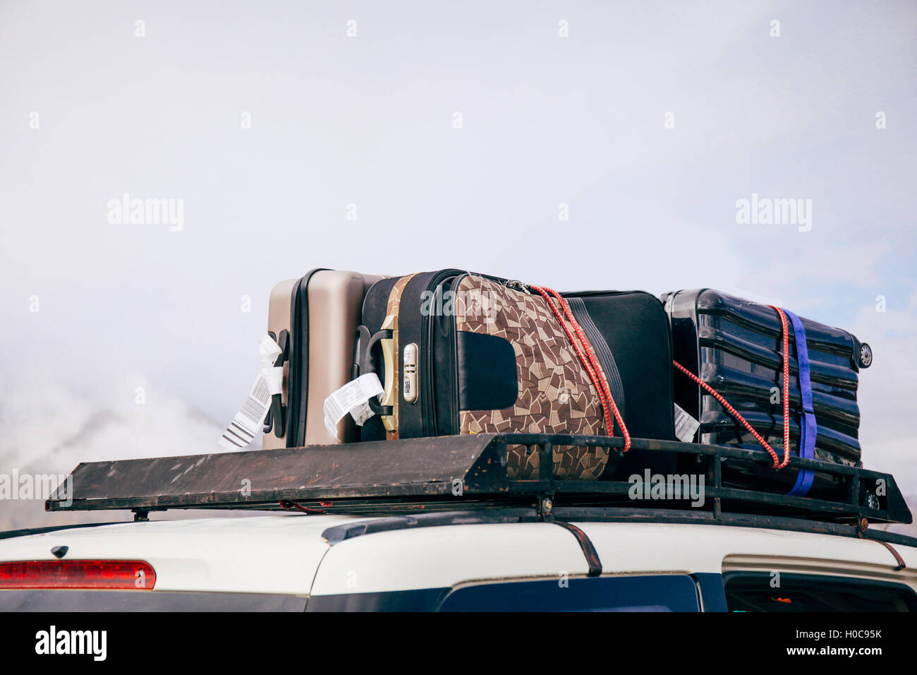 Koffer und Taschen auf dem Autodach bereit für eine Reise im Himmelshintergrund angeordnet Stockfoto