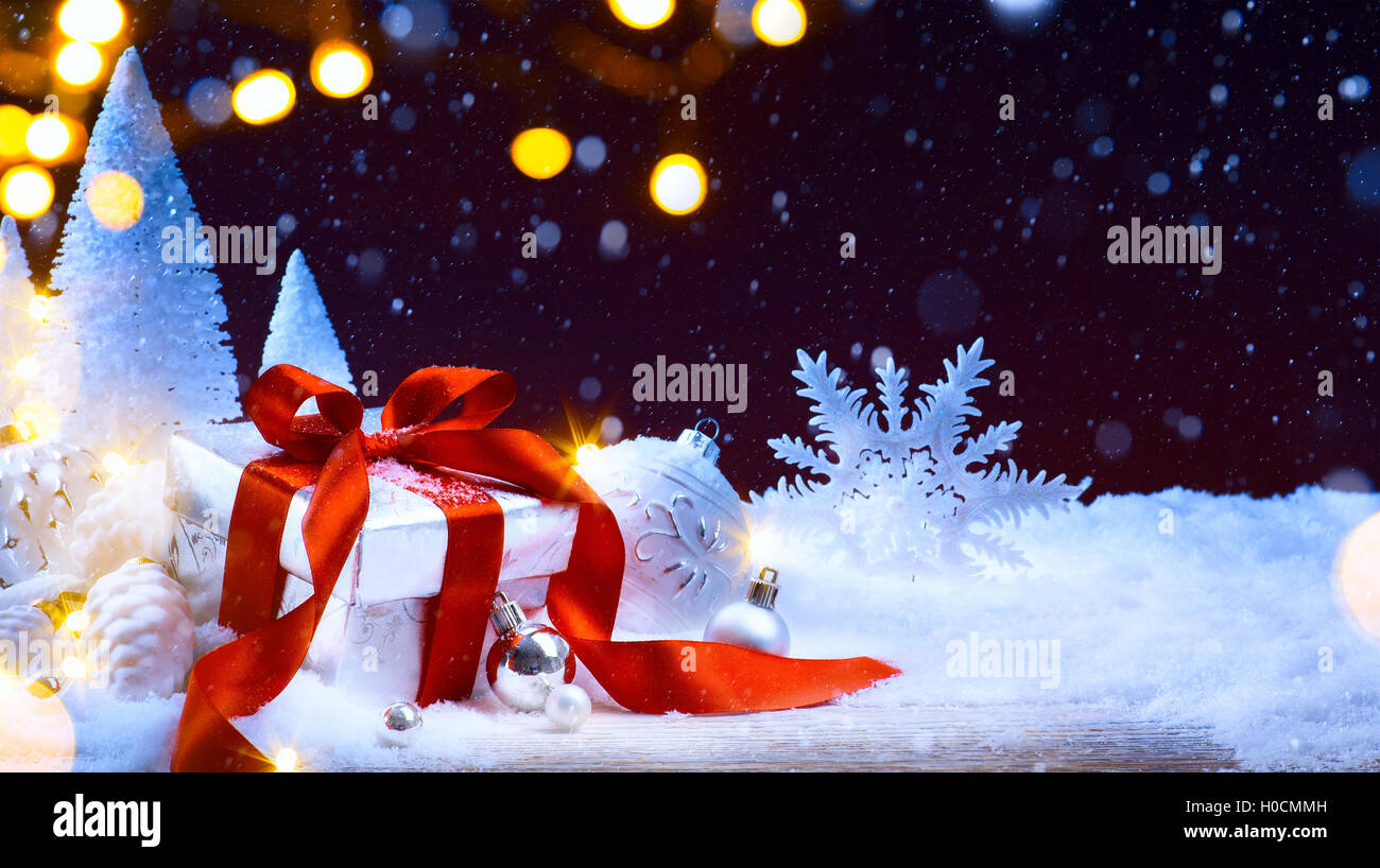 Weihnachtsbaum-Licht; festlichen Hintergrund mit Christbaumkugeln und Geschenk-Box auf Schnee Stockfoto