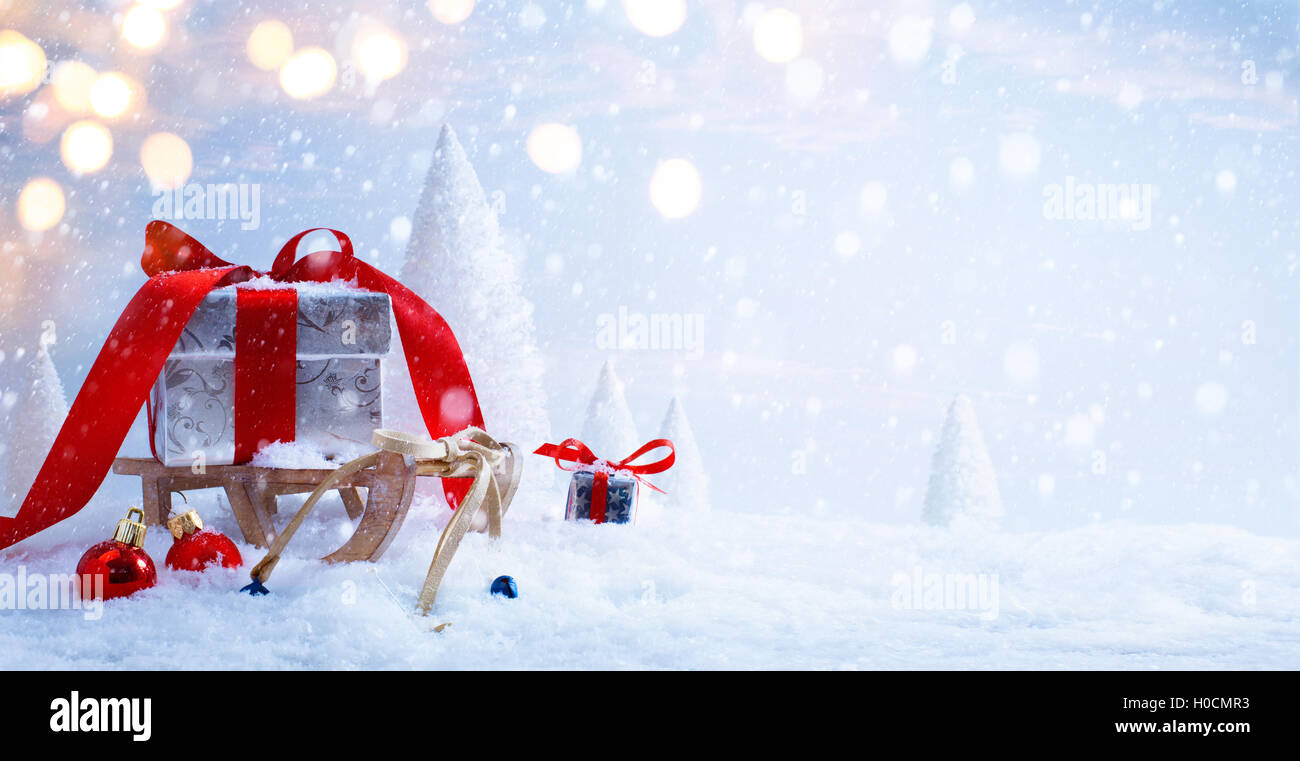 Der Schlitten des Weihnachtsmannes mit Weihnachtsgeschenke auf dem Hintergrund der schneebedeckten Bäumen Stockfoto