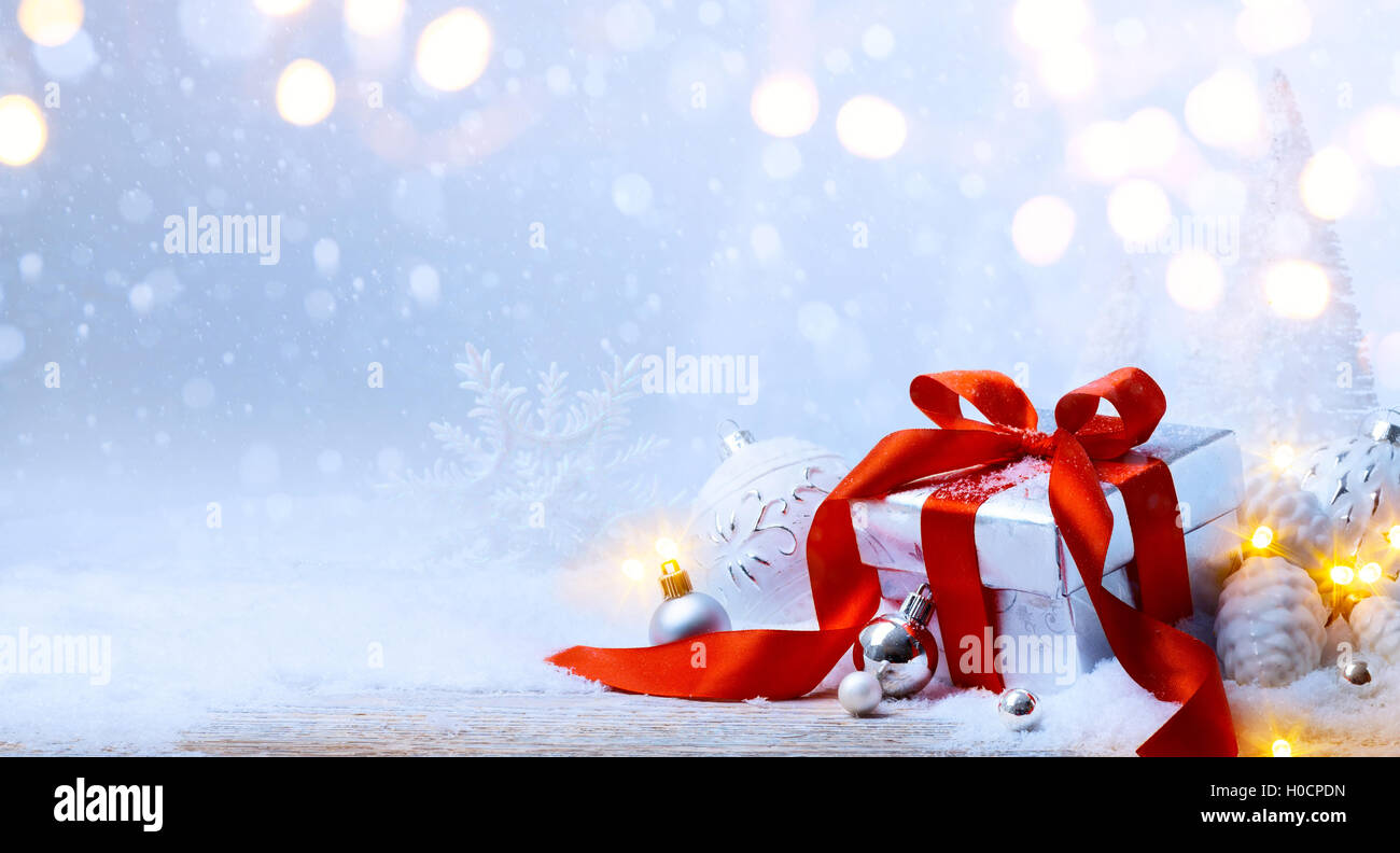 Weihnachtsbaum-Licht; festlichen Hintergrund mit Christbaumkugeln und Geschenk-Box auf Schnee Stockfoto