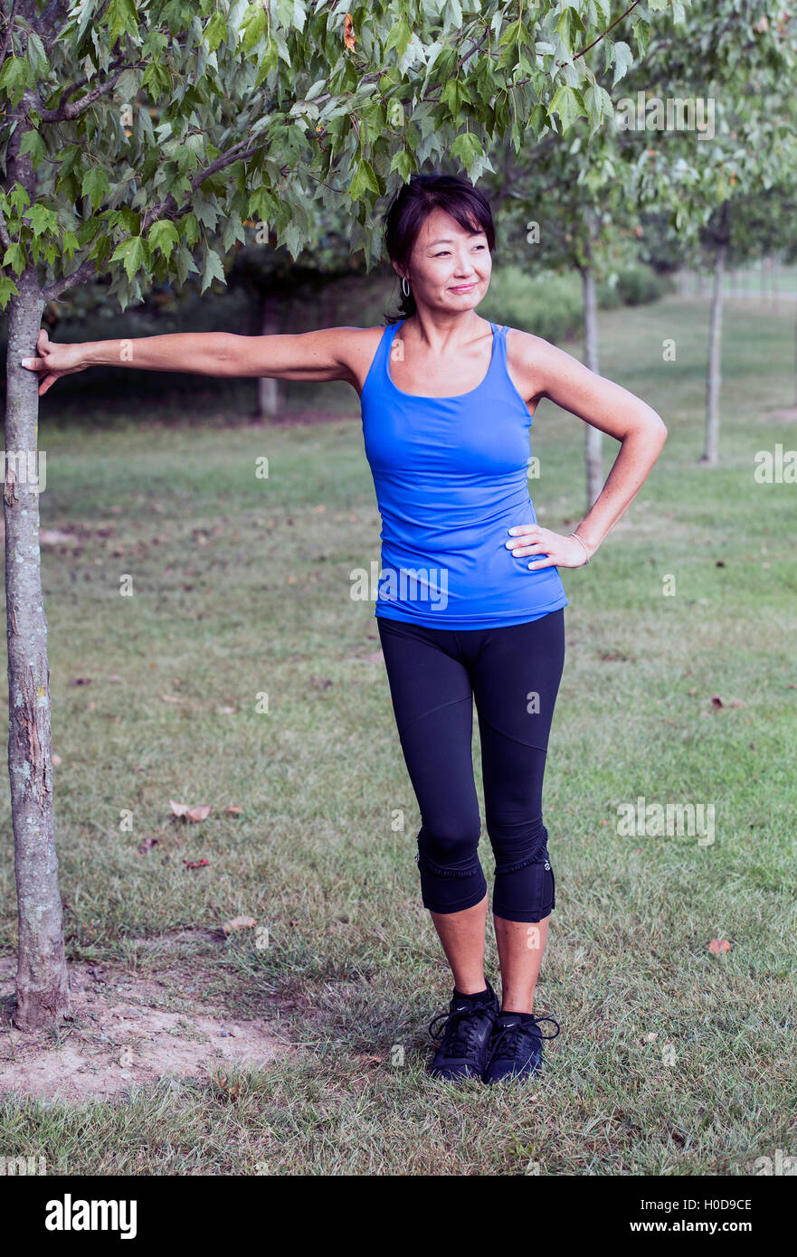 Asiatisch-amerikanische Frau, die an einen Baum gelehnt Stockfoto