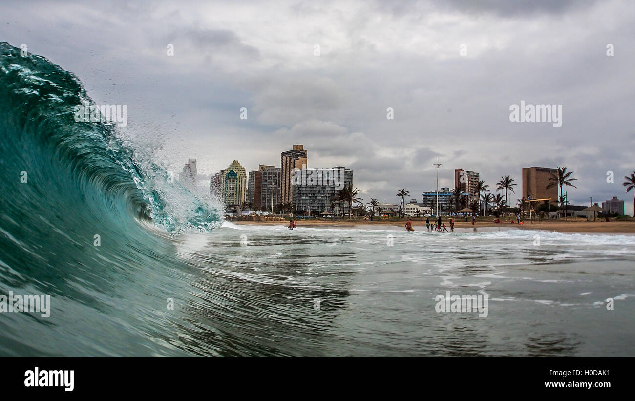 Eine Welle bricht in der Nähe einige Schwimmer in Durban, Südafrika Stockfoto