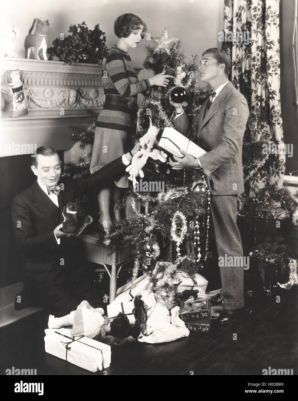 Männer helfen Frau Weihnachtsbaum zu Hause dekorieren Stockfoto