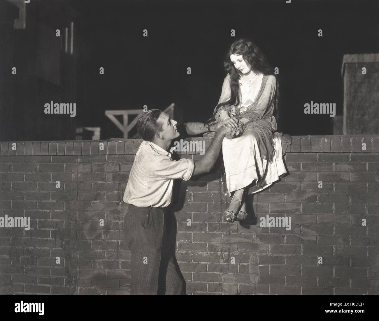 Mann Kunrad Frau sitzen auf Ziegelmauer Stockfoto