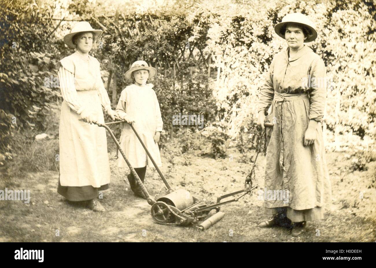 Frauen mit einem als Esel zieht die Maschine und die Mutter und die Tochter schob den Rasen zu mähen. Stockfoto