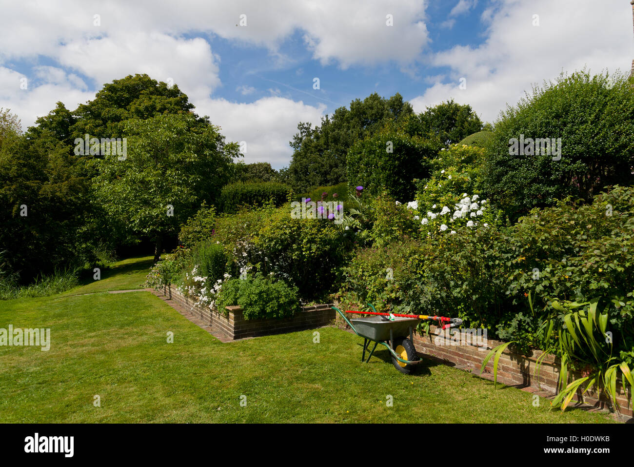 Schubkarre und Beschneiden Werkzeug in einem englischen Garten. Sommer Blick auf grünen Garten. Stockfoto